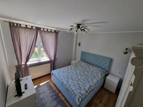 a small bedroom with a blue bed and a window at Yla Apartments in Piatra Neamţ