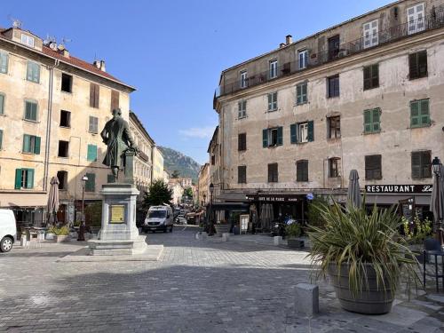 una estatua en medio de una ciudad con edificios en Joli appartement F2 centre ville de Corte, en Corte