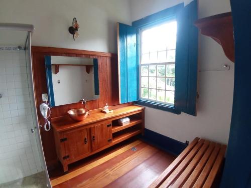 a bathroom with a sink and a mirror and a window at HOTEL FAZENDA PACIENCIA in Santana dos Montes