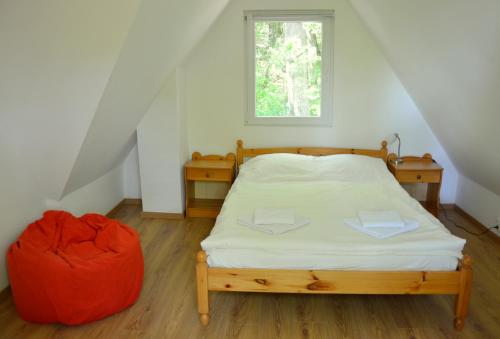 1 dormitorio con cama con almohada roja y ventana en Vércse Vendégház en Kismaros