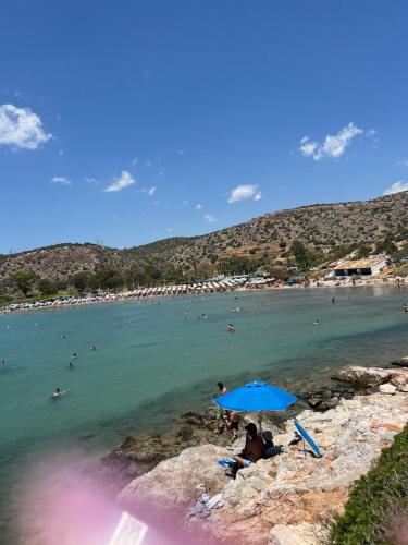 a group of people sitting under an umbrella on a beach at Ruby’s Apartment 5 min to the sea in Vari