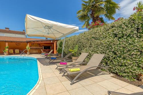 a pool with chaise lounge chairs and an umbrella at Apartment Complex Irena with Pool in Poreč