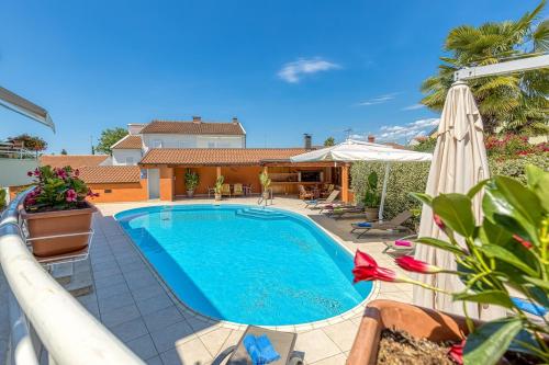 a swimming pool with an umbrella and a house at Apartment Complex Irena with Pool in Poreč