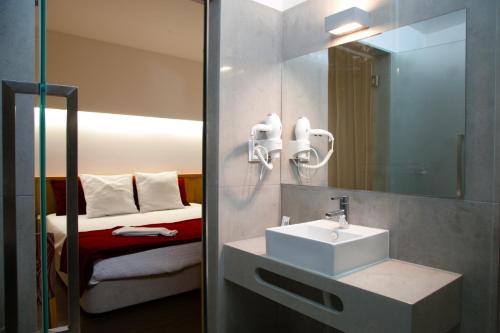 uma casa de banho com um lavatório, um espelho e uma cama em Casa Avé Maria em Fátima