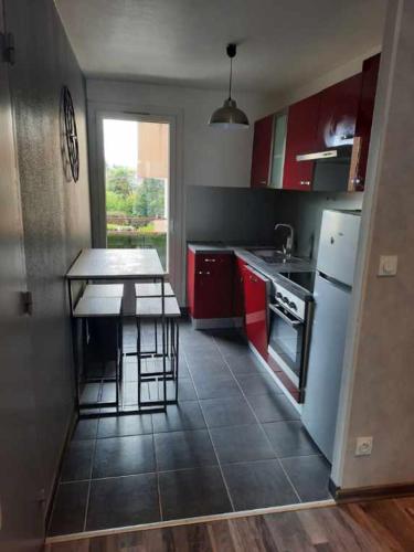 une cuisine avec des armoires rouges et un réfrigérateur blanc dans l'établissement tres bel appartement et situation au top, à Saint-Martin-dʼHères