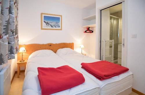 a white bed with two red pillows on it at Les Balcons PROCHE PARC NATIONAL VANOISE appartements 2 pieces 8 pers in Termignon