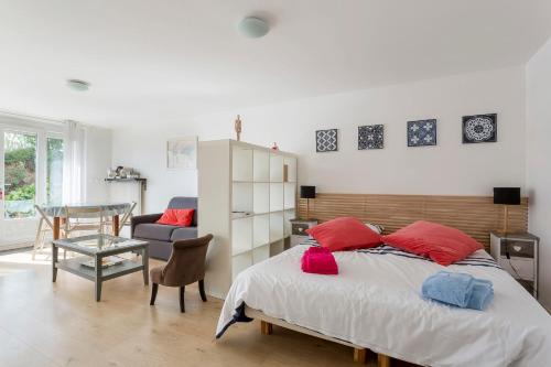 Schlafzimmer mit einem Bett mit roten Kissen und einem Tisch in der Unterkunft Studio du Maréchal in Sainte-Foy-lès-Lyon