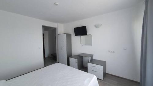 ein weißes Schlafzimmer mit einem Bett und einem Flachbild-TV in der Unterkunft Къща за гости - Пролет in Lozenets