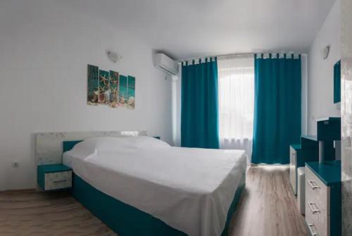 a bedroom with a large bed and blue curtains at Къща за гости - Пролет in Lozenets