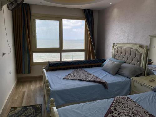a bedroom with two beds and a large window at Amazing Sea View 2 bedroom apartment in Alexandria