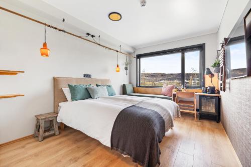 a bedroom with a large bed in a room with windows at The Greenhouse Hotel in Hveragerði