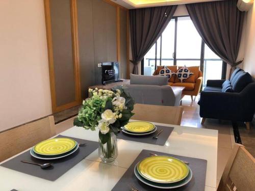 a living room with a table with yellow plates and flowers at R&F Princess Cove by StayHere - 3BR in Johor Bahru