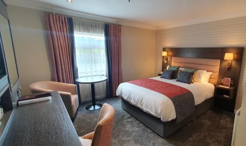 um quarto de hotel com uma cama grande e uma cadeira em Burrendale Hotel Country Club & Spa em Newcastle