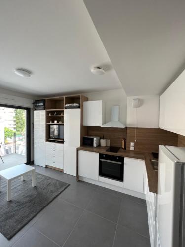 une cuisine avec des armoires blanches et une table à l'intérieur dans l'établissement Appartement tout équipé centre ville Menton, à Menton