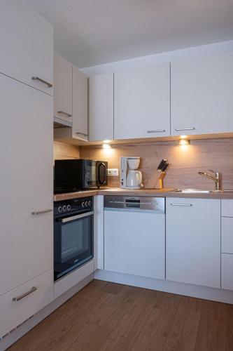 a kitchen with white cabinets and a stove top oven at Gästehaus Alpenstern in Ehrwald