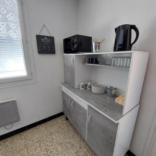 a kitchen with a white cabinet with drawers at Le Chant de l'Alyte in Lens-Lestang