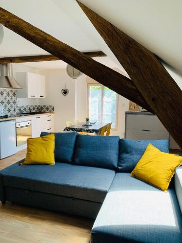 um sofá azul com almofadas amarelas numa cozinha em Centre ville (2): superbe appartement climatisé em La Flèche