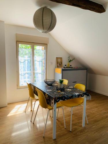 a dining room with a table and yellow chairs at Centre ville (2): superbe appartement climatisé in La Flèche