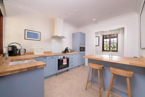 Una cocina con gabinetes azules y taburetes de madera. en The Queen's Hut, en Aboyne