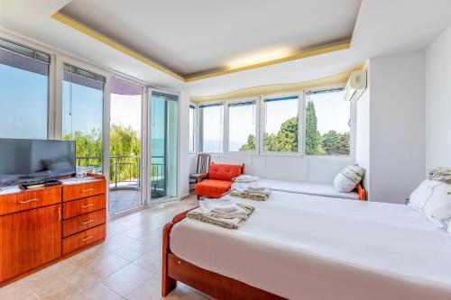 um quarto com uma cama, uma televisão e janelas em Villa Swiss em Ohrid