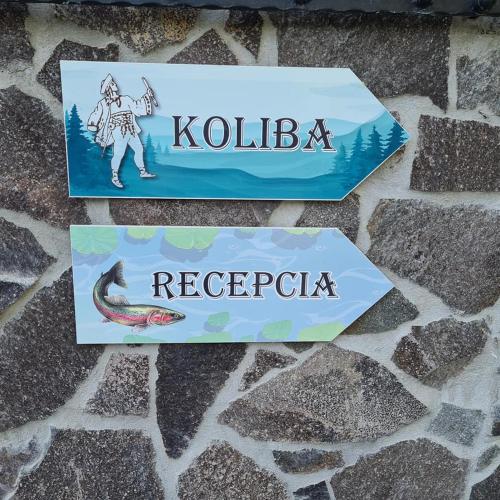 two signs on a stone wall with the words krollk reebok at Penzión Dúhový Pstruh in Bystrá