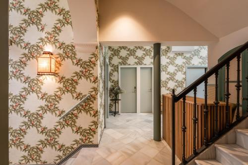 a hallway with a staircase with floral wallpaper at BYPILLOW Abril in Seville