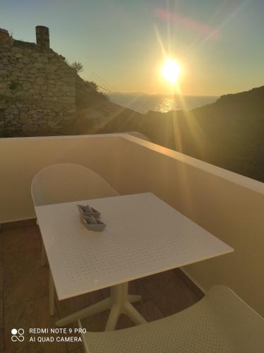 a white table and chairs on a balcony with the sunset at GRΕΛΙΑ ΗΟΜΕ in Naxos Chora