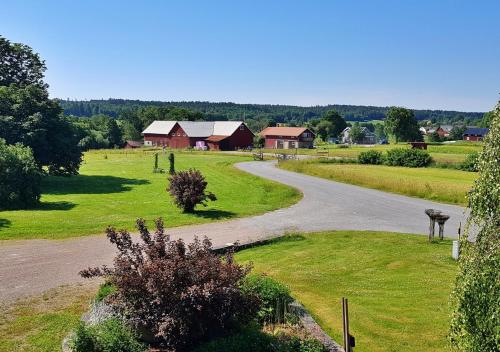 un camino sinuoso en un campo con casas a lo lejos en Flora Dekor gästgård, en Alingsås