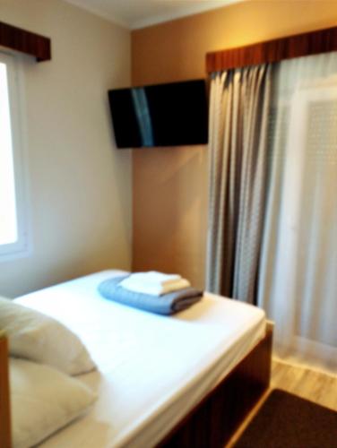 a bedroom with a bed with a television on the wall at ΕΚΑLI ROOMS APARTMENTS in Kalentzi
