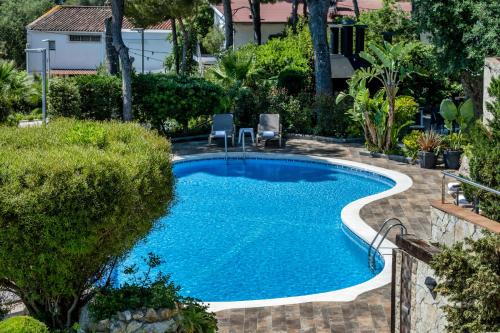 a swimming pool with two chairs in a yard at Apartamentos Marivent by Brava Hoteles in Platja  d'Aro