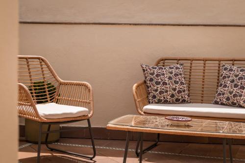 two wicker chairs and a table and a couch at BYPILLOW Abril in Seville