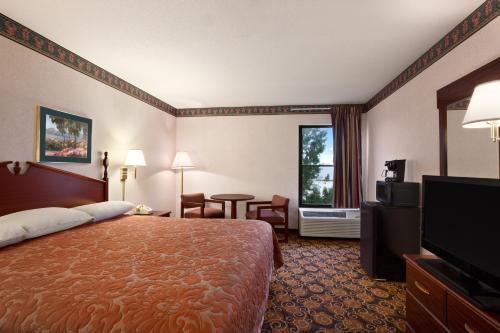 a hotel room with a bed and a flat screen tv at Super 8 by Wyndham Evansville North in Warrenton