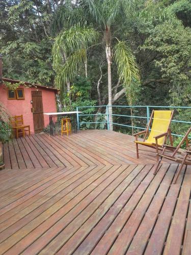a wooden deck with a yellow chair and a table at Pousada Estância Rio Acima in Itamonte