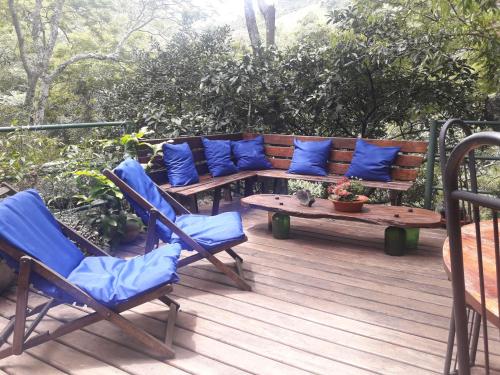 a wooden bench with blue pillows on a deck at Pousada Estância Rio Acima in Itamonte