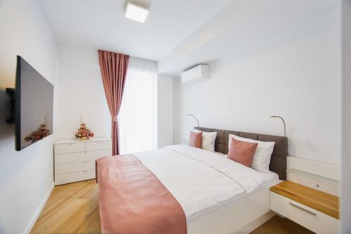 a bedroom with a large bed and a television at Pink Sahara near City Center in Oradea
