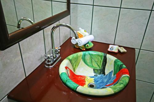 a bathroom sink with a bird painted on it at Manatus Hotel in Tortuguero