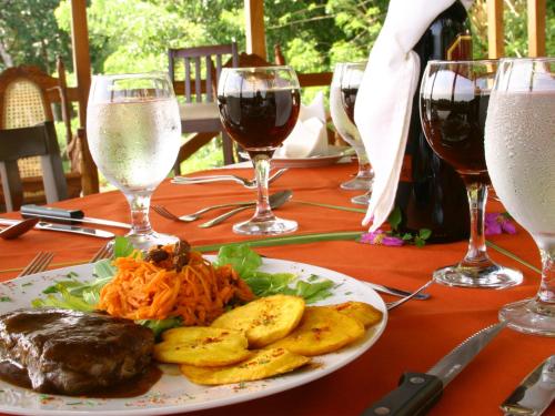a plate of food on a table with glasses of wine at Manatus Hotel in Tortuguero