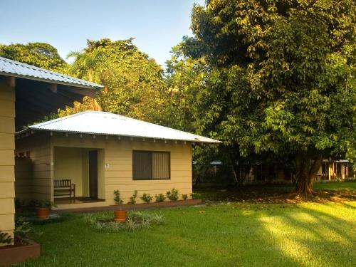 a small yellow house with a tree in the yard at Manatus Hotel in Tortuguero