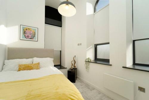 a bedroom with a bed with yellow sheets and windows at Spacious 2 bedroom city centre apartment in Leeds