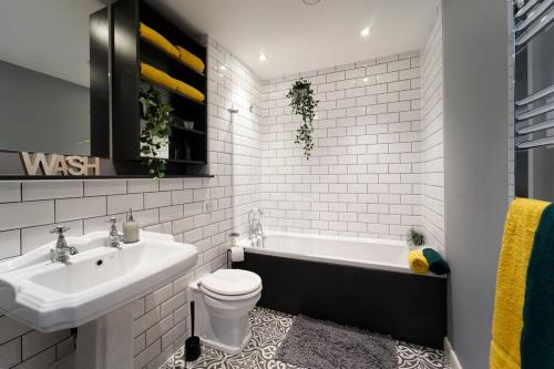a bathroom with a tub and a toilet and a sink at Spacious 2 bedroom city centre apartment in Leeds
