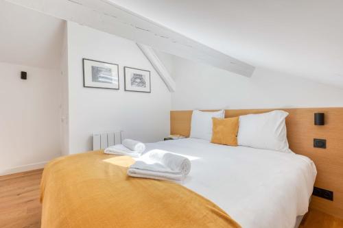 een slaapkamer met een groot bed met witte lakens en oranje kussens bij Les Cottages de Montmartre - Secret Courtyard in Parijs