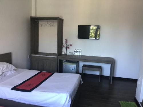 a bedroom with a bed and a desk and a television at Ki Nô Homestay in Hoi An