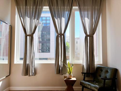 a room with a chair and two windows with curtains at Stay at Luna on Ridge Ave in Philadelphia