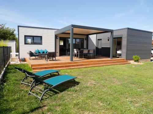 a house with a deck with a table and chairs at Atlantic Lodge in Brétignolles-sur-Mer