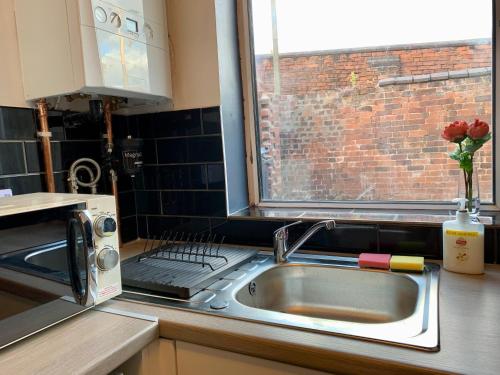 a kitchen with a sink and a window and a microwave at Lovely 1 bedroom, 4 guests service apartment in Doncaster