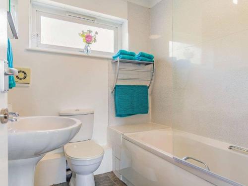 baño blanco con lavabo, aseo y ventana en Lovely Magnolia Apartment 6 single beds en Torquay