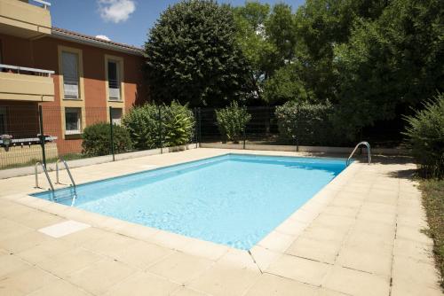 a large blue swimming pool in front of a building at APPARTEMENT TOULOUSE - PISCINE ET PARKING PRIVE in Toulouse