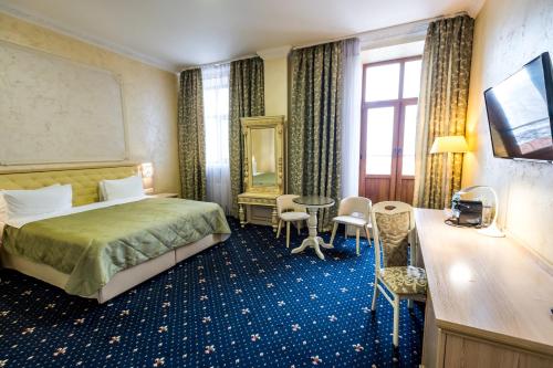 une chambre d'hôtel avec un lit, une table et des chaises dans l'établissement Hotel France, à Vinnytsia