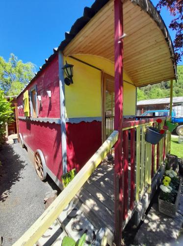 a red yellow and red trailer with a porch at Le Ranch du Madres in Roquefort-de-Sault