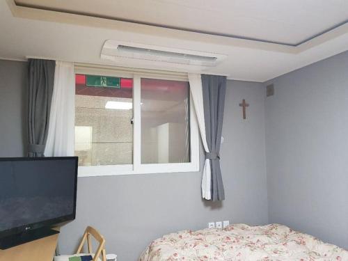 - une chambre avec une fenêtre, un lit et une télévision dans l'établissement Gyeongbokgung Palace Seochon Christian Home - Foreigner Only, à Séoul